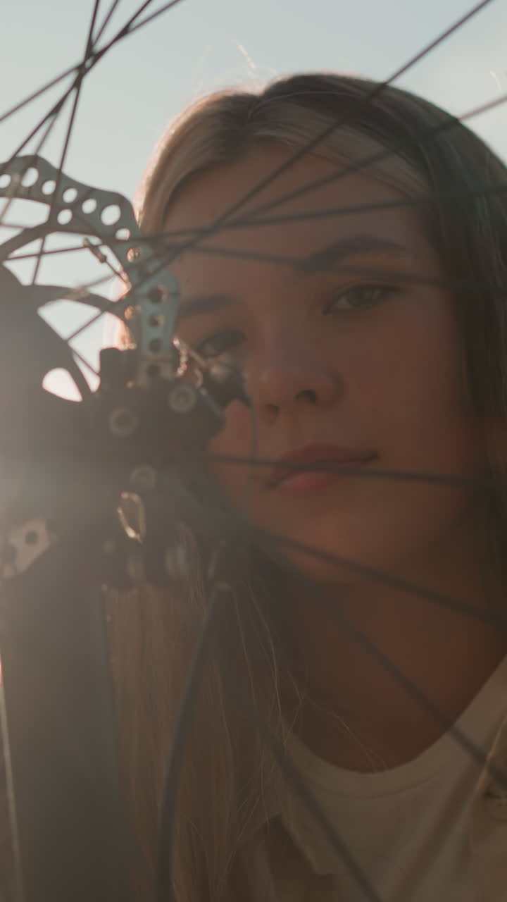 ciclista tocando suavemente la rueda de su bicicleta, radiando con una cálida sonrisa mientras la luz del sol brilla sobre ella y la rueda gira, este momento captura su alegría y conexión con el ciclismo