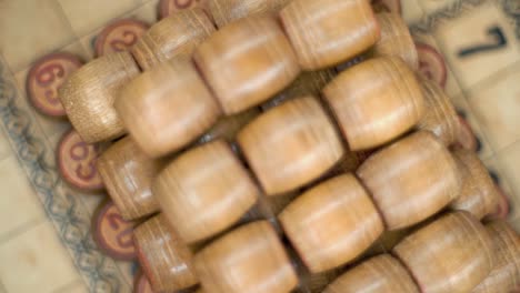 cinematic creative smooth dreamy rotating macro shot from above of bingo wooden barrels in a row, woody figures, old numbers background, vintage board game, slow motion 120 fps commercial gimbal video