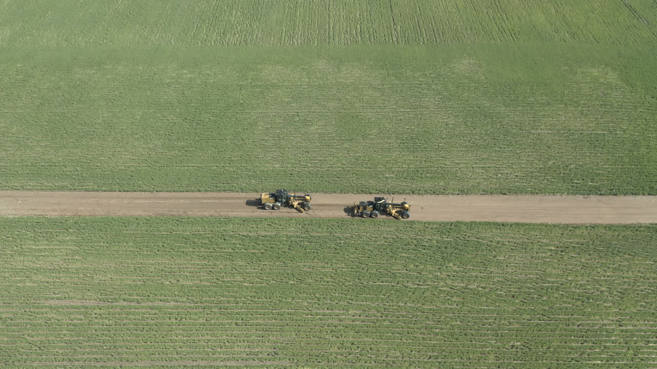 캐나다 서스캐처원의 그린 필드 사이의 도로 그레이더의 상위 뷰
