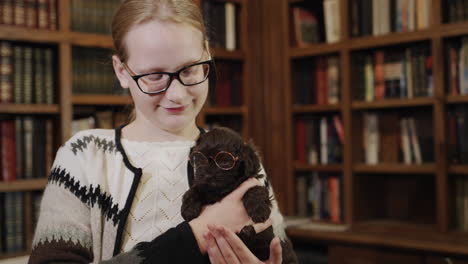 happy child in the library are a girl and a puppy with glasses. cute pets and education