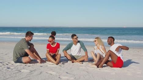 Junge-Erwachsene-Freunde-Sitzen-Am-Strand-Und-Unterhalten-Sich-In-4K