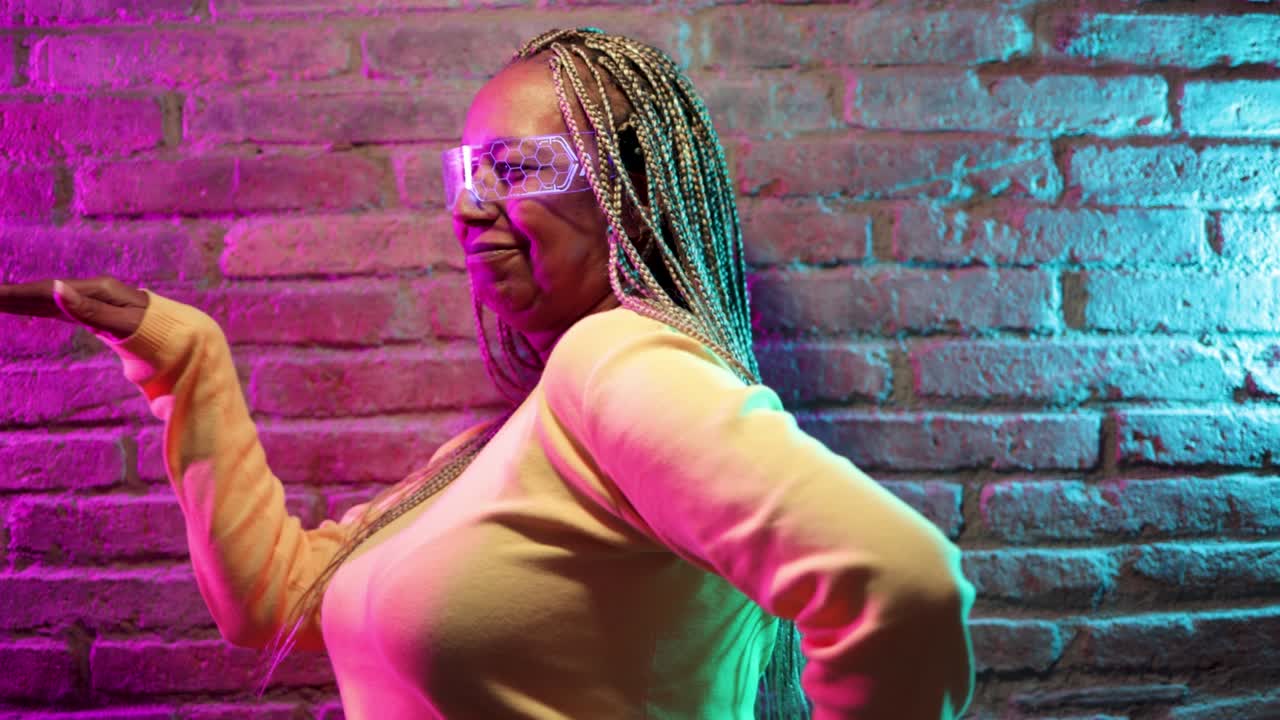 Happy senior African woman dancing and wearing futuristic augmented reality glasses