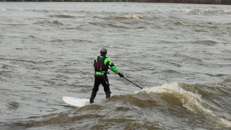 man surfing the wake of a wave on the ottawa river during flood season with a long board