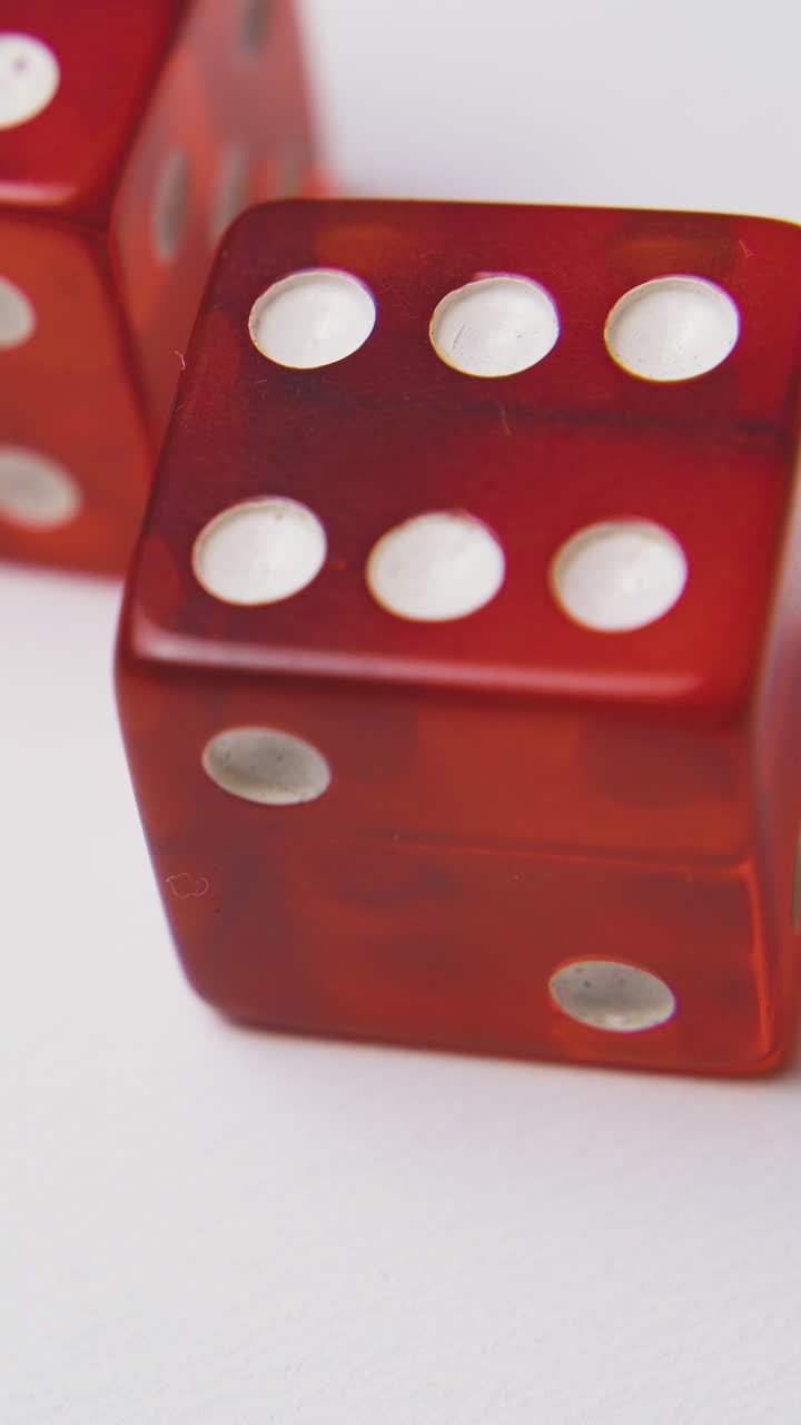 person hand throws beautiful red plastic dices with white spots on light background extreme close view