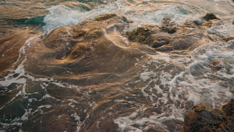 Close-up-shot-of-rough-ocean-waves-crushing-against-the-volcanic-rocky-coastline