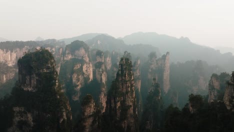 aerial shot of forest-covered sandstone towers stretching toward distant misty mountains in zhangjiajie national park's dramatic terrain