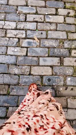 woman walking on a cobblestone street in a floral dress