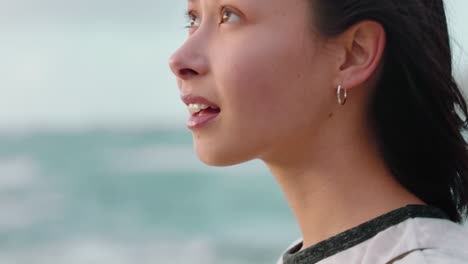 Retrato-De-Una-Mujer-Asiática-Feliz-Disfrutando-De-La-Libertad-Con-Los-Brazos-Levantados-Sintiendo-Alegría-En-La-Playa-Al-Atardecer-Explorando-La-Pasión-Por-Los-Viajes-Con-El-Viento-Soplando-El-Pelo