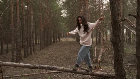 Alegre-Hermosa-Mujer-Divirtiéndose-En-El-Bosque-Disfrutando-De-La-Libertad,-Caminando-Sobre-Un-Tronco-Caído