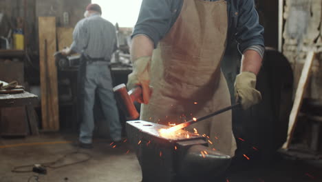 blacksmith hammering hot iron on anvil