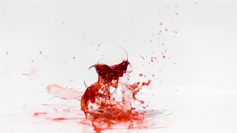 rompiendo el vaso de vino tinto en cámara lenta sobre un fondo blanco