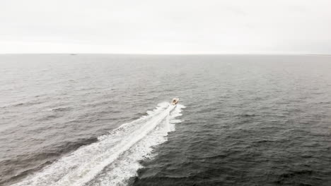 aerial shot of one lone motor boat speeding through the endless waves of the open ocean