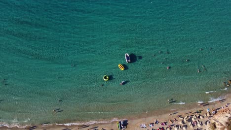 People-enjoy-summer-fun-in-the-sea-and-on-the-beach-in-Crete,-Greece