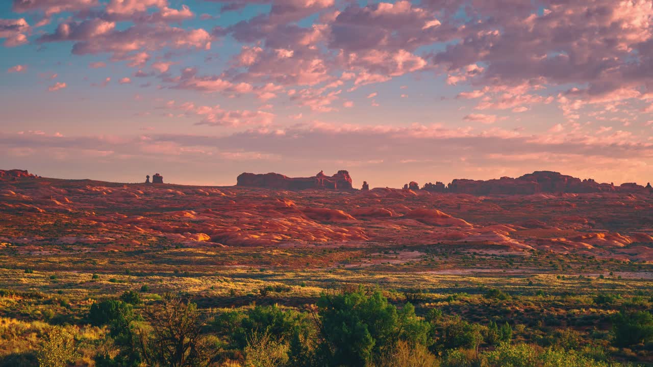 Beautiful 4K sunrise time-lapse video at Utah's Arches National Park with red morning clouds passing by.