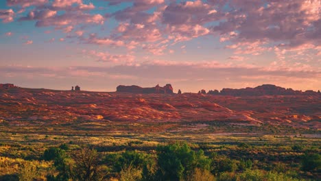 beautiful 4k sunrise time-lapse video at utah's arches national park with red morning clouds passing by.
