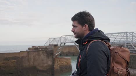 Man-on-vacation-looks-around-at-seascape-on-the-docks-of-Biarritz-France