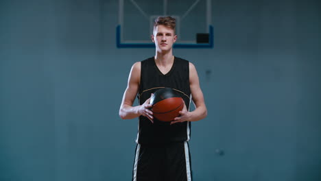 retrato de media longitud de un jugador de baloncesto caucásico posando con una pelota en el interior. 4k uhd