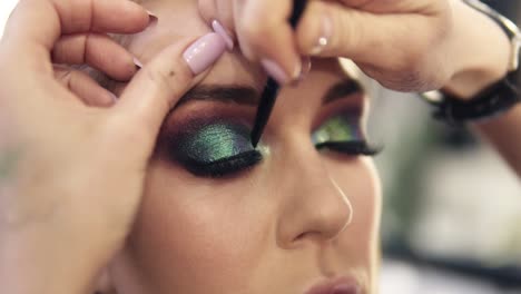 Final-touches-of-visagist-work-to-complete-green-eyes-make-up-for-a-gourgeous-woman.-Shine-shadows