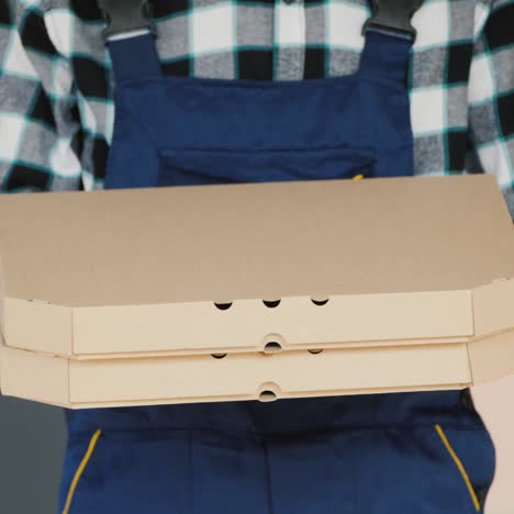 a courier holds the pizza box in protective gloves to deliver it safely