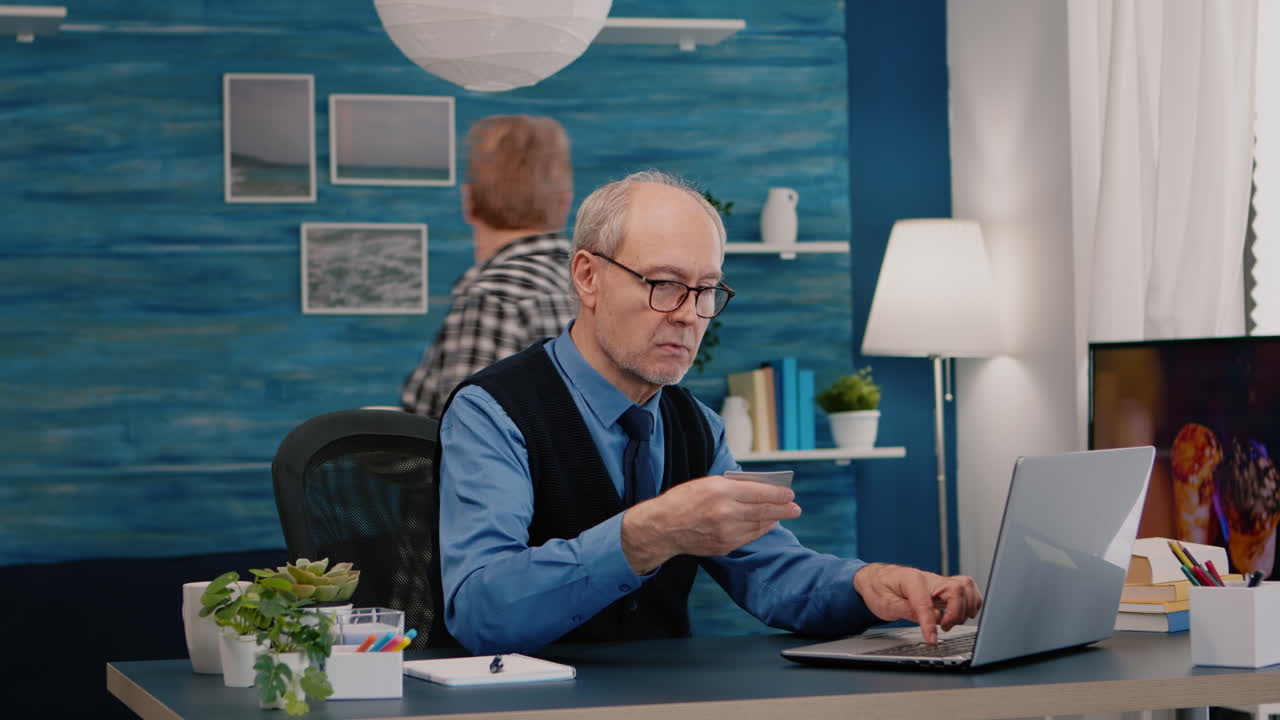 Retired man making online payment using credit card on laptop