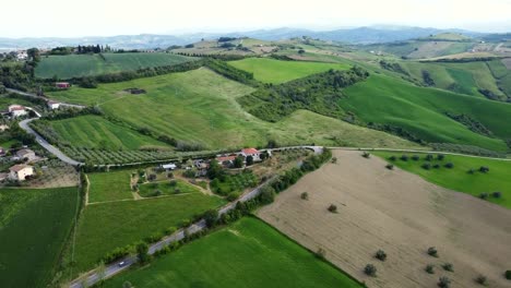 Toma-Aérea-De-Un-Paisaje-Montañoso-Con-Campos-De-Tierra-Y-Fincas