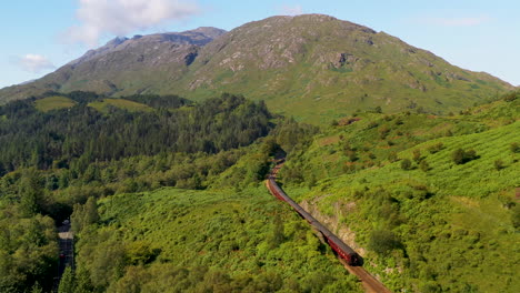 wide revealing drone shot of train in the glenfinnan viaduct