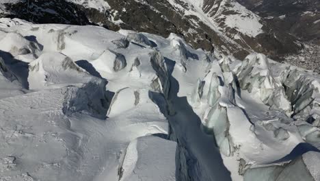 Aerial-view-of-icy-snow-covered-peaks-in-the-Swiss-alps,-valley-downhill