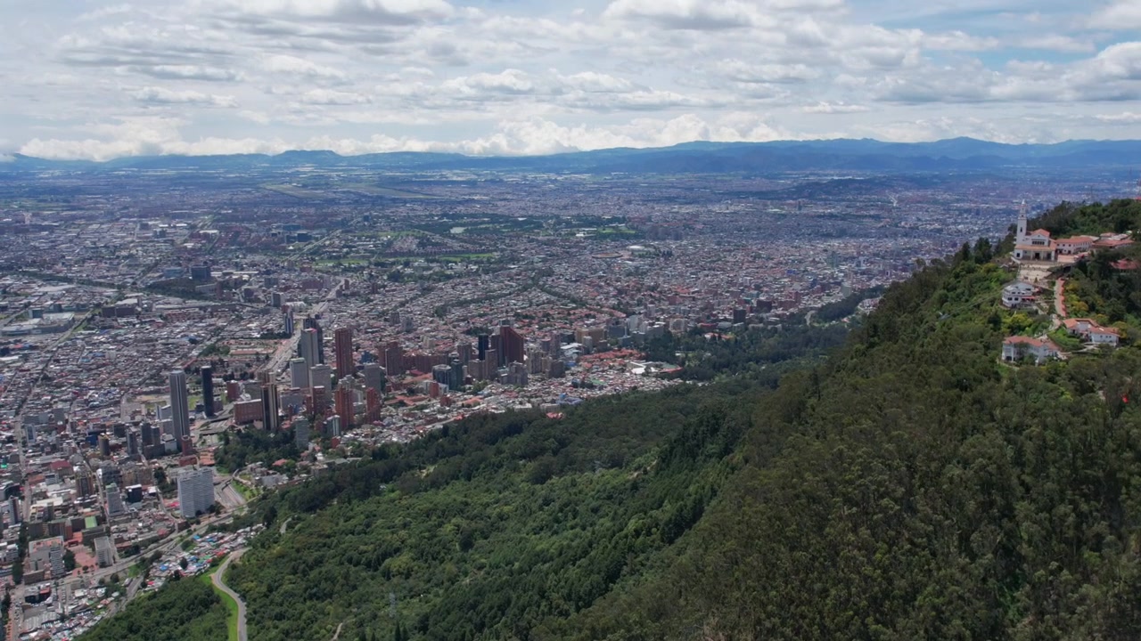 Dron leci w kierunku panoramy Bogoty z zalesionego wzgórza z Andami w tle