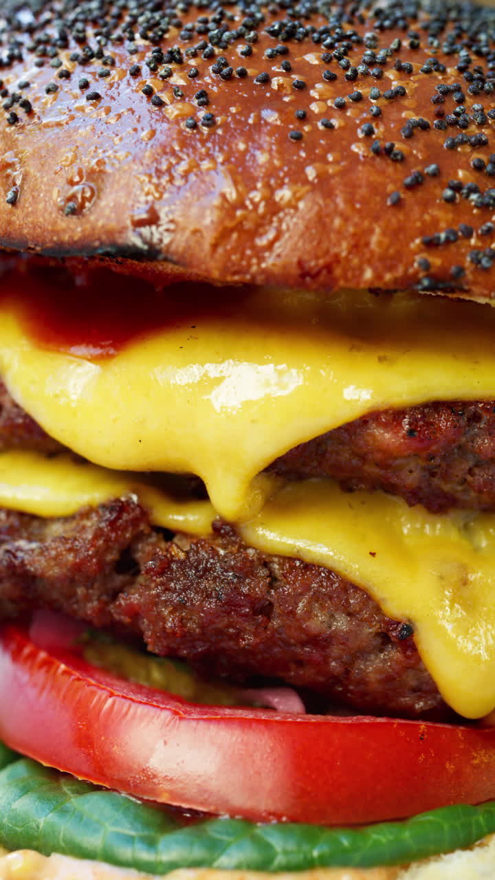 Close up of a big hamburger on a table at a restaurant. Vertical