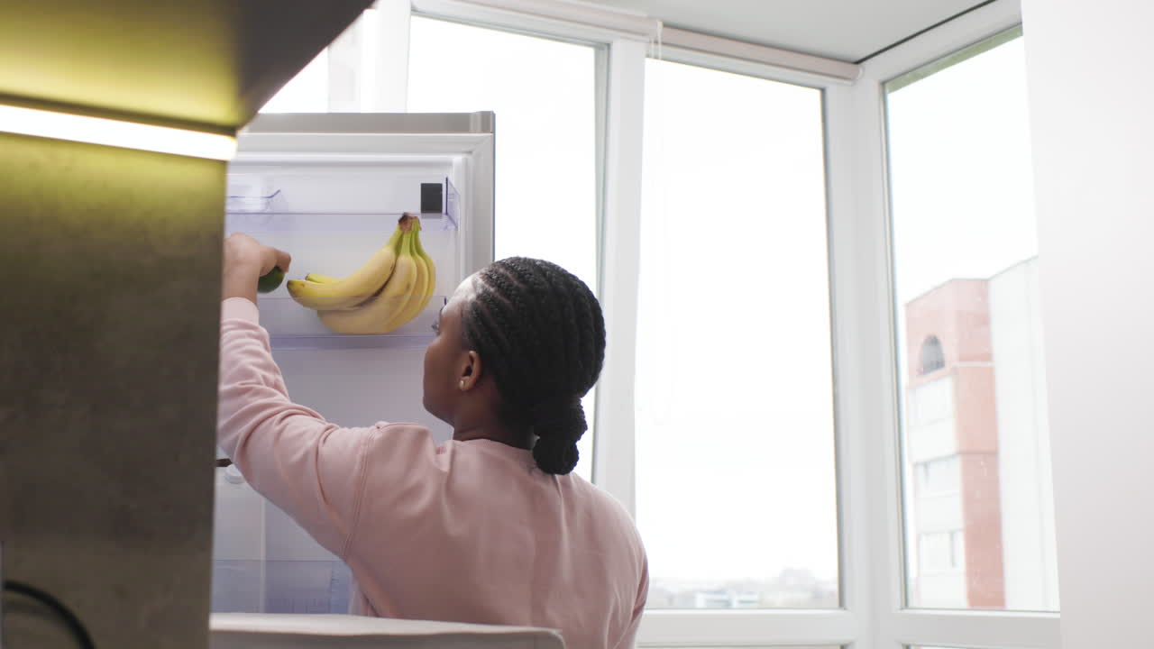 mujer tomando un aguacate del refrigerador