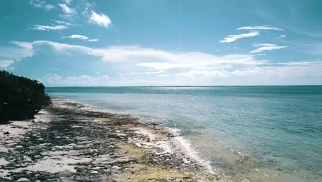 Perfect-fast-forwards-slowly-rise-up-drone-shot-of-a-lonely-dream-beach-at-midday-noon-time