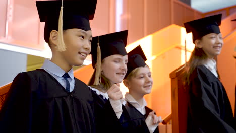 Side-View-Of-Happy-Kindergarten-Students-In-Cap-And-Gown-Dancing-And-Having-Fun-During-The-Preschool-Graduation-Ceremony