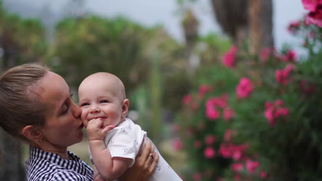 Surrounded-by-palm-trees-and-colorful-flowers-at-the-resort,-a-mother-delights-in-playful-interactions-with-her-child,-offering-hugs-and-kisses.-The-scene-exudes-family-happiness