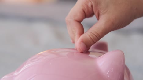 inserting coin into piggy bank