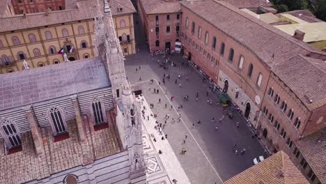 Antena-Arriba-Hacia-Abajo-Del-Centro-Histórico-De-La-Ciudad-De-Siena-Con-Reunión-Turística-En-La-Plaza-Principal-Del-Duomo-De-La-Catedral,-Pueblo-Medieval-En-Toscana-Italia-Destino-De-Vacaciones