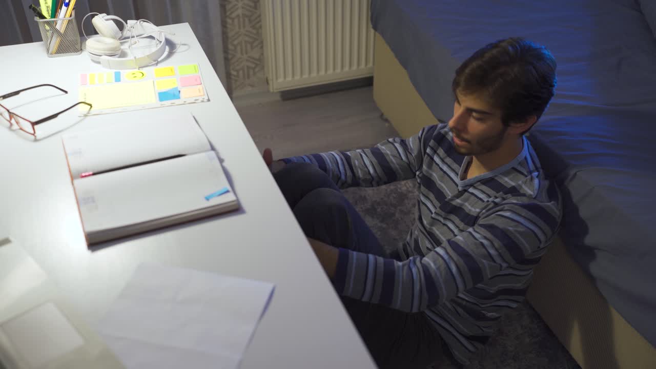 Thoughtful young man in bedroom feeling unhappy and worried about future.