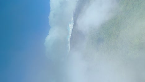 vuelo a través de nubes con fondo de montaña, volando a través de las nubes vista de la cabina con densas montañas de bosque de hoja perenne y cielo azul, verdadero video aéreo vertical 4k para redes sociales, modo de retrato 9:16