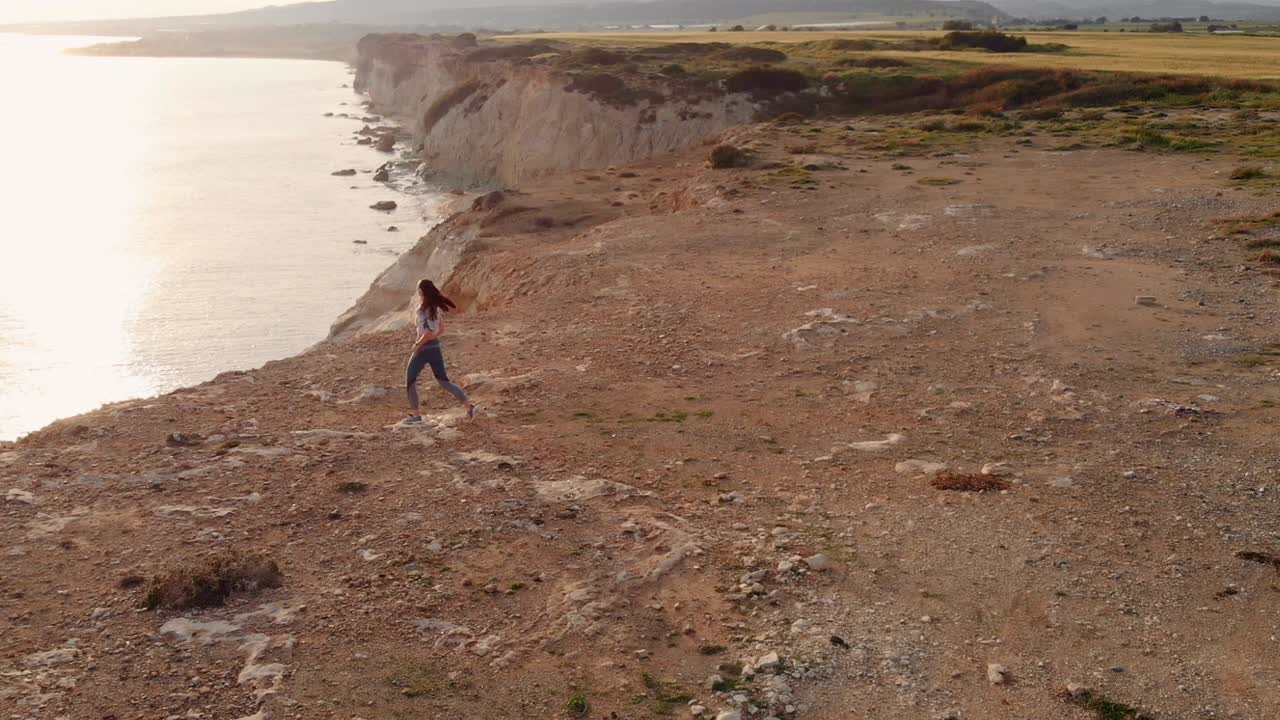 vista desde arriba de la mujer corriendo sobre las rocas de la orilla del mar