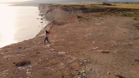 view from above of woman running on sea shore rocks