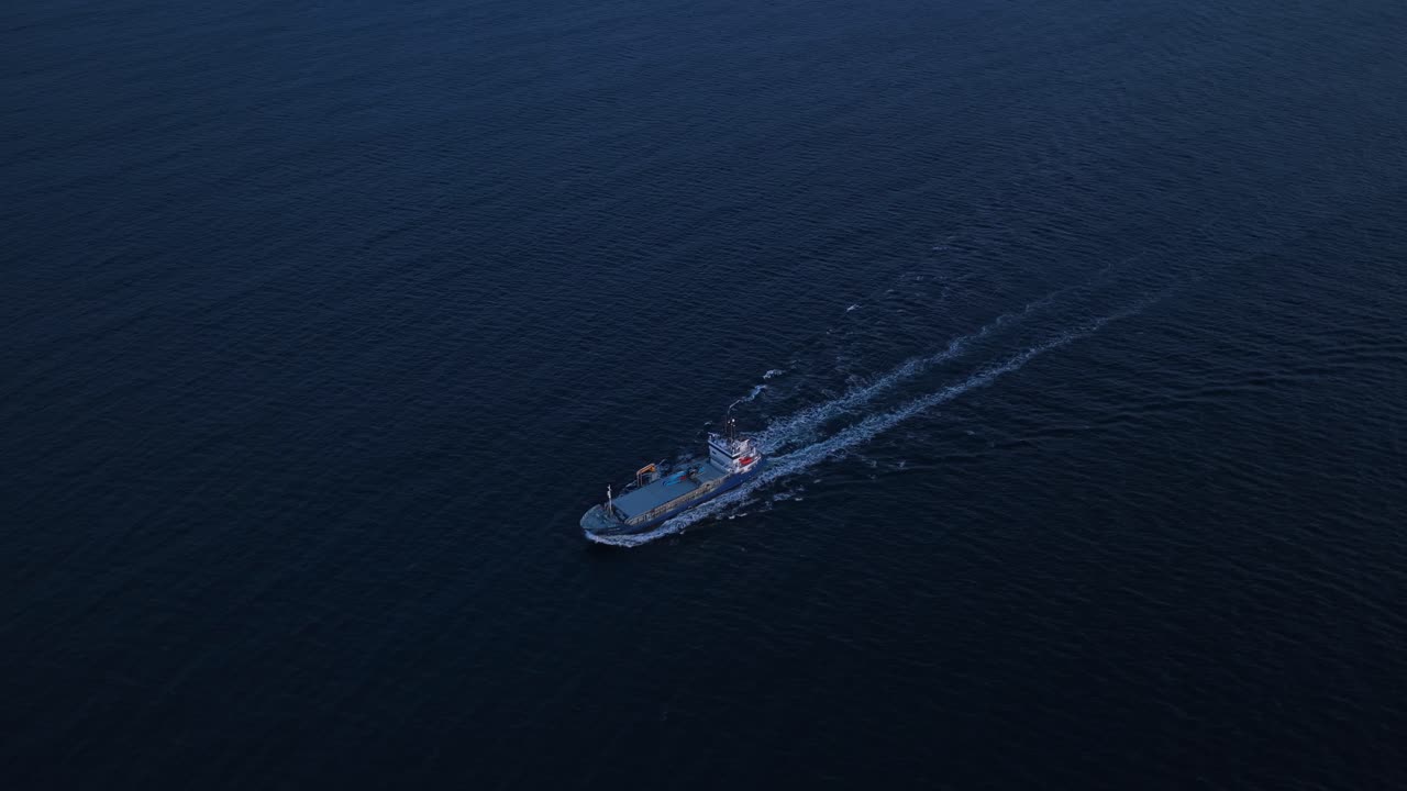 Veduta aerea di una grande imbarcazione che solca le calme acque dell'oceano all'alba, al largo della costa di Smola.