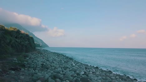 cinematic aerial video of waves spashing to big pile of rocks in a late afternoon in valugan boulder beach in batanes, philippines