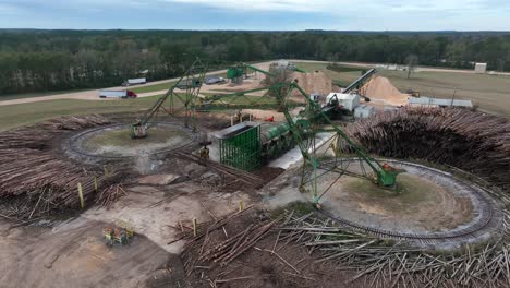 crane equipment lifts pine tree logs into shredder