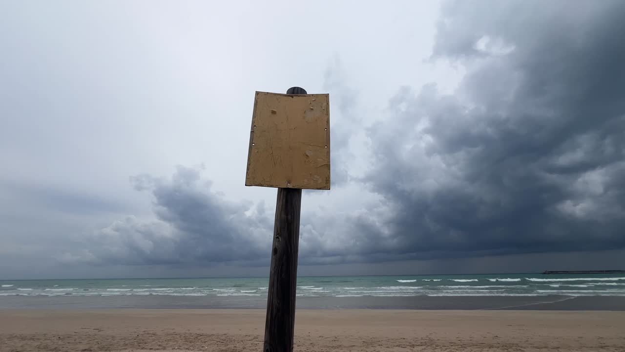 Close-up shot of a sign on the beach sand at sunset