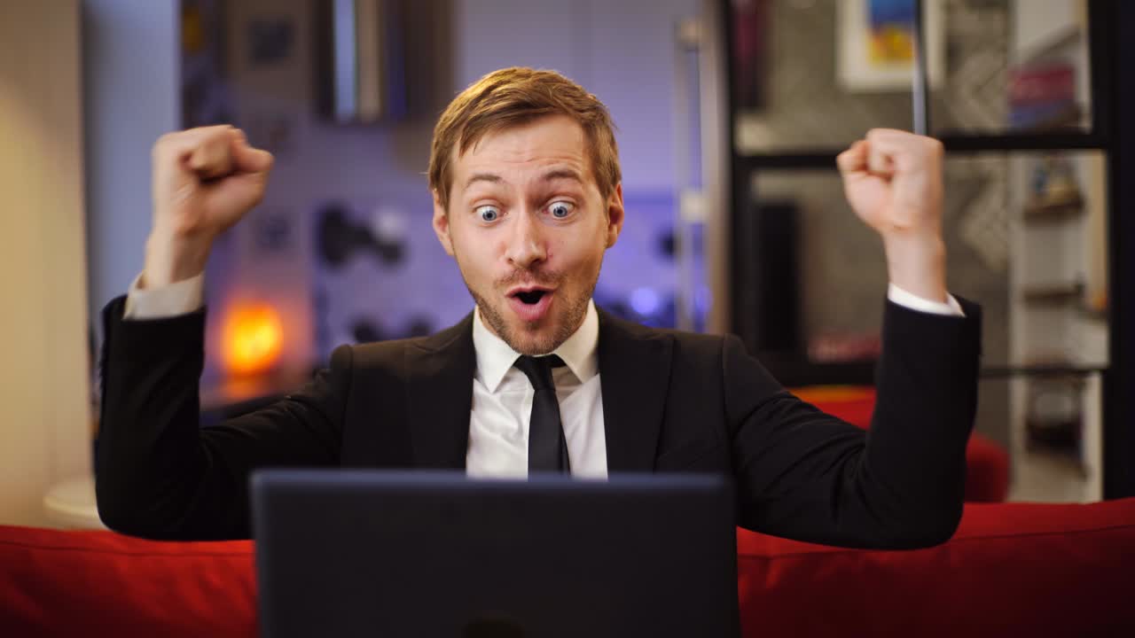 매우 흥분한 사업가, 슈트를 입고 회사 수입의 성장을 축하하고, 그의 손은 주먹으로 들어올렸다.