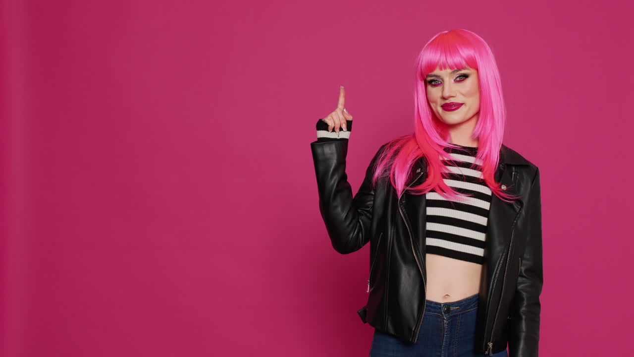 Trendy female model pointing up with index fingers on camera