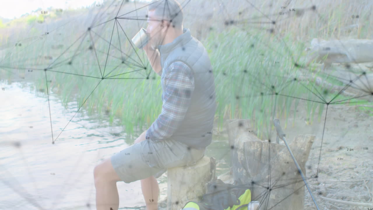 male hiker sitting lakeside raising mug, displaying network overlay nodes for technology theme