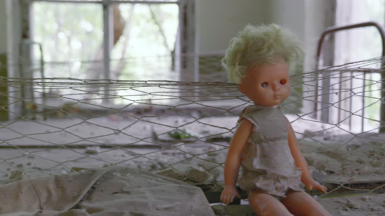Alte, schmutzige Puppen sitzen auf dem Bett in einem verlassenen Kindergartengebäude in der Stadt Pripyat nahe Tschernobyl, Ukraine – Schwenkaufnahme.
