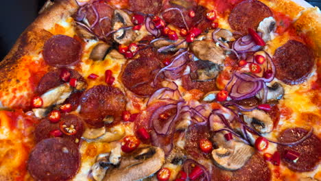 Traditional-Italian-spicy-pepperoni-pizza-with-fresh-chili-peppers,-red-onions-and-mushrooms,-real-authentic-Neapolitan-pizza,-delicious-food,-4K-shot