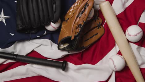 overhead baseball still life with catchers mitt on american flag as bat and ball are thrown into frame