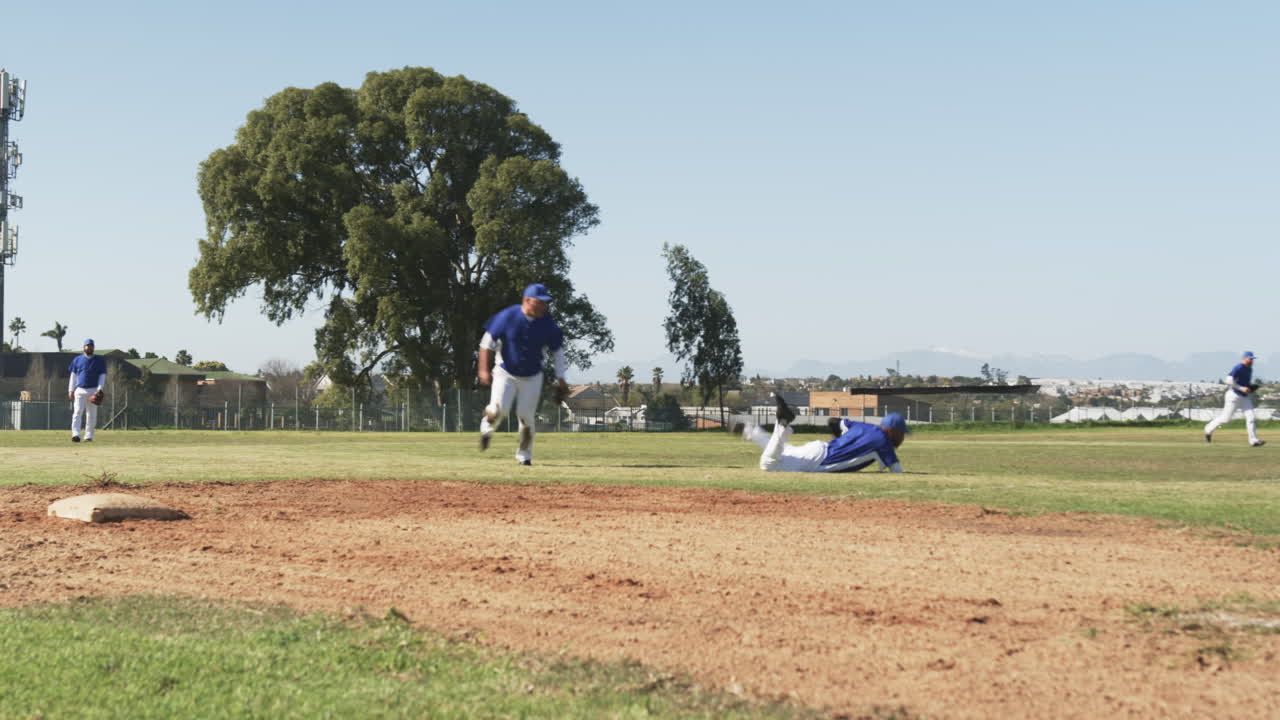 Playing baseball, players running and sliding on field during game